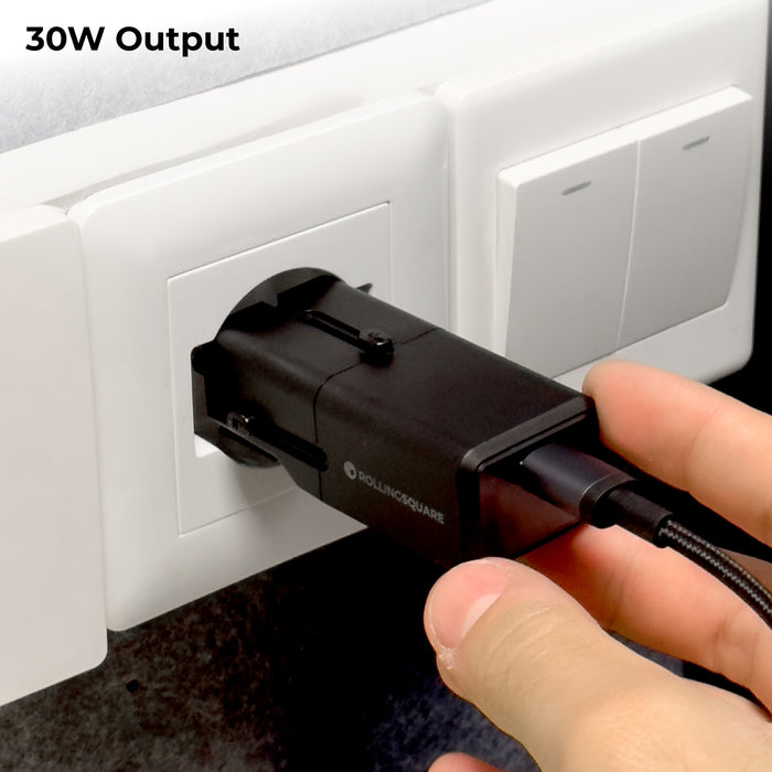 Pocket Travel Charger - US/EU/UK/AU plugs - Pocket Travel Charger - US/EU/UK/AU plugs - 30W - 1 Port - Compact black 30W travel charger plugged into a white wall socket with attached USB-C cable. - Rolling Square Pocket Travel Charger - US/EU/UK/AU plugs - 30W - 1 Port - Compact black 30W travel charger plugged into a white wall socket with attached USB-C cable. - Rolling Square