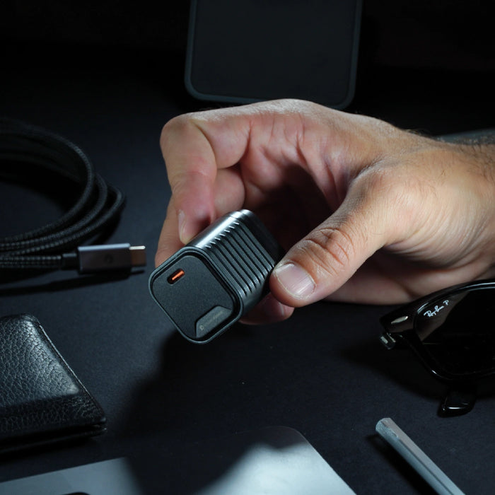 Supertiny 65W + Free 2in1 Cable (Bundle) - US - Compact black 65W USB-C charger with foldable prongs held in hand against dark background. - Rolling Square