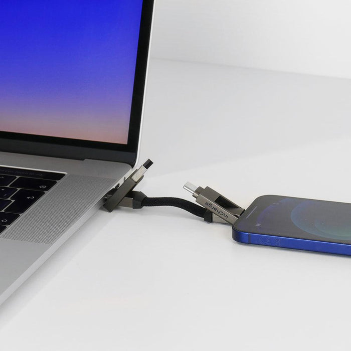 inCharge® 6 - 15W, 6in1 keyring cable - Mercury Gray - Compact black six-in-one keyring charging cable connected between a silver laptop and a blue smartphone. - Rolling Square