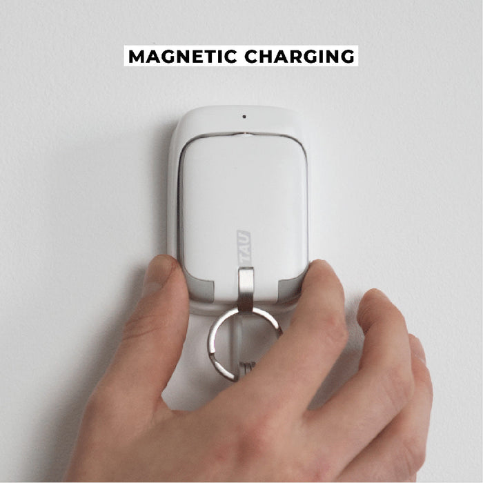 TAU® - Always-charged power bank - Charcoal Black - Compact white power bank with keyring attached, held by hand on white magnetic charger panel. - Rolling Square