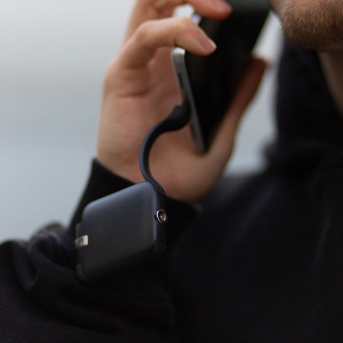 TAU® - Always-charged power bank - Charcoal Black - Compact charcoal black power bank connected to a phone with a short charging cable. - Rolling Square